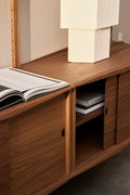 DK3 System Ultra walnut cabinet with sliding doors, one open, with a table lamp and a book on top