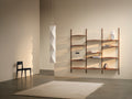 DK3 System Ultra in oiled oak, wall rails with shelves in a room with a rug and a chair