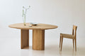 DK3 Tangent Table Round in oiled oak with a wooden chair in a white room