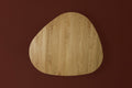DK3 Tangent Table Round in oiled oak seen from above with one extension leaf, on a deep red background