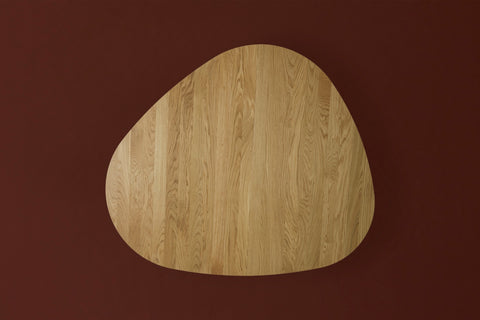 DK3 Tangent Table Round in oiled oak seen from above with one extension leaf, on a deep red background