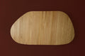 DK3 Tangent Table Round in oiled oak seen from above with two extension leaves, on a deep red background