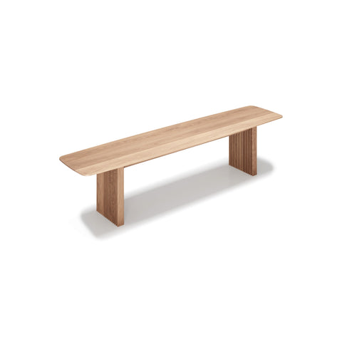 DK3 Ten Bench in Soaped Oak, solid wood dining bench with grooved legs and a curved top, angled view on white