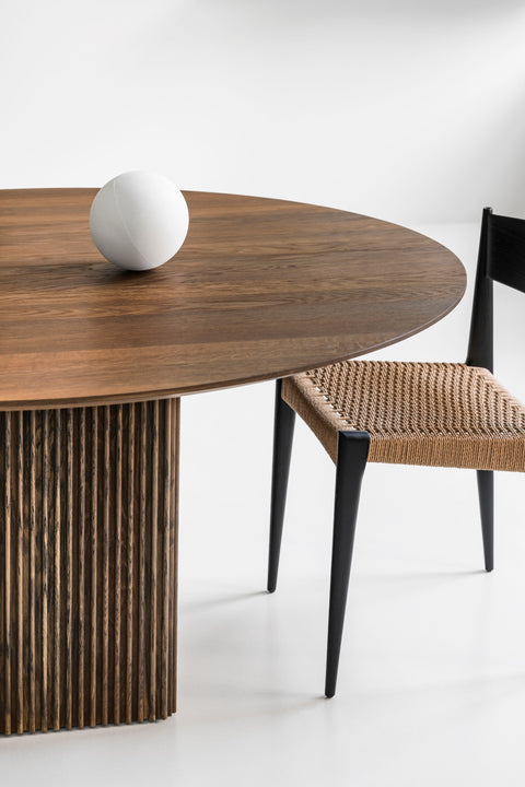DK3 Ten Table Round in smoked oak with a paper cord chair, close view of the fluted base