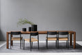 DK3 Jeppe Utzon Table #1 in walnut set with black framed paper cord chairs in a dining room with a grey wall