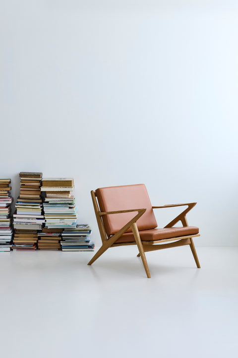 DK3 Z Chair in oiled oak with cognac leather, beside stacks of books