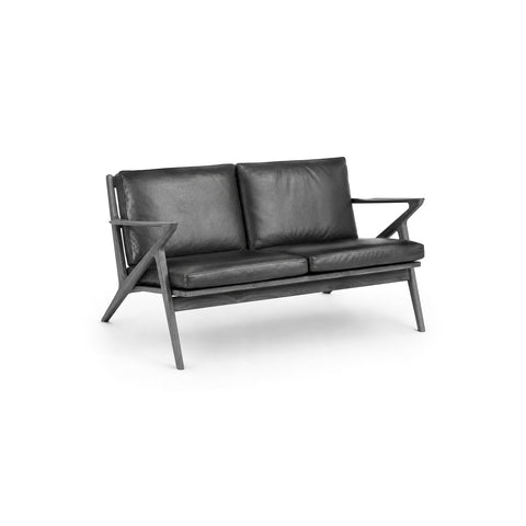 DK3 Z Sofa, 2 Seater in Rio Leather Black 0500 and Black Lacquered Oak, leather two-seat sofa with a Z-shaped solid wood frame, angled view on white