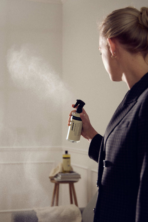 Humdakin Room Spray 2-in-1, Salvia & Sea Buckthorn, odour neutralising room spray, a woman in a dark blazer spraying it in a living room