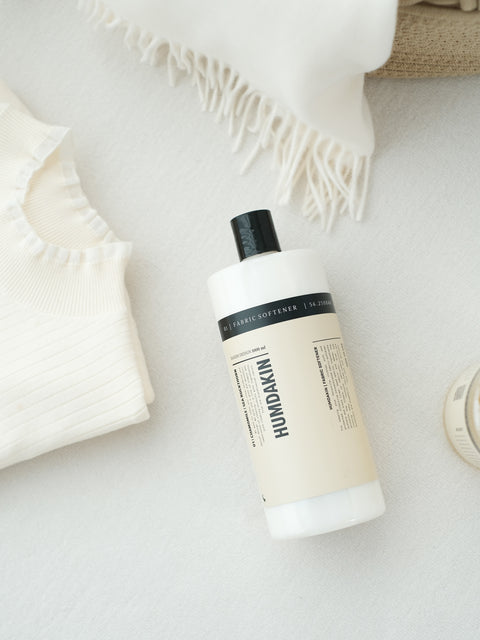 Humdakin 01 Fabric Softener, Chamomile & Sea Buckthorn, liquid fabric softener, bottle lying on a white knitted throw seen from above