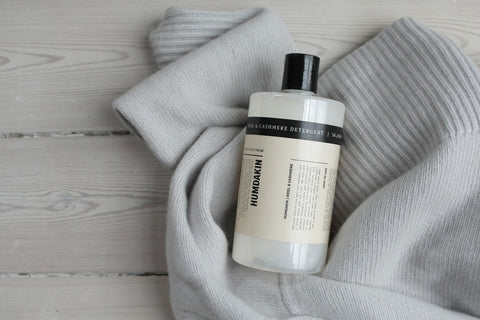 Humdakin 01 Wool & Cashmere Detergent, wool wash detergent, bottle lying on a grey knit sweater on a pale wood floor