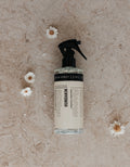 Humdakin Room Spray 2-in-1, Salvia & Sea Buckthorn, odour neutralising room spray, bottle on a stone surface with small daisies