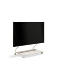 Pedestal Disco TV Stand in Oat, minimalist low TV stand with an integrated shelf holding a flat screen TV, on a plain white background