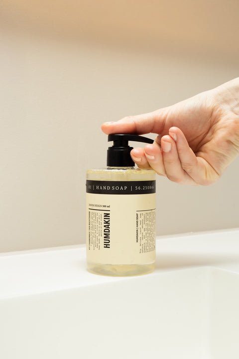 Humdakin 01 Hand Soap, Chamomile & Sea Buckthorn, liquid hand soap, a hand pressing the pump on a cream bathroom counter