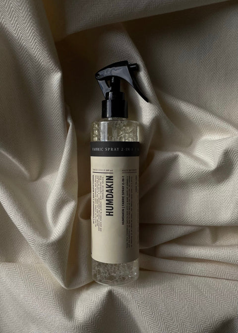 Humdakin Fabric Spray 2-in-1, Chamomile & Sea Buckthorn, textile refresher spray, bottle lying on a white bedsheet