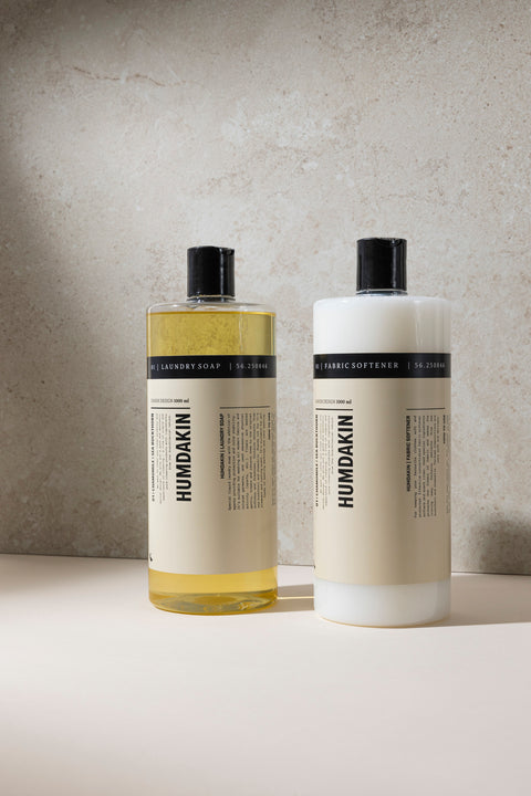Humdakin 01 Laundry Soap, Chamomile & Sea Buckthorn, liquid laundry detergent, laundry soap and fabric softener bottles side by side against a grey wall