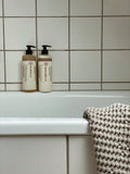 Humdakin 01 Conditioner, Chamomile & Sea Buckthorn, hair conditioner, bottles on the edge of a bathtub against white tiles with a knit towel