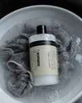 Humdakin 01 Wool & Cashmere Detergent, wool wash detergent, bottle standing in an enamel bowl with a knit soaking in a sink