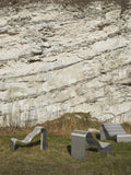 Muuto Dream View Benches in brushed steel placed outdoors against a natural rock wall backdrop