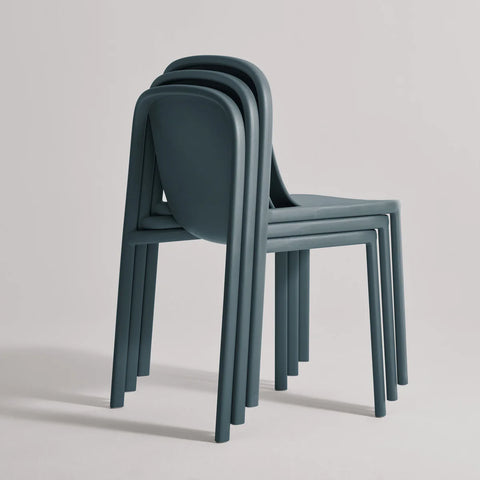 Blu Dot Decade Chairs in marine blue recycled plastic, three chairs stacked together demonstrating the stackable design