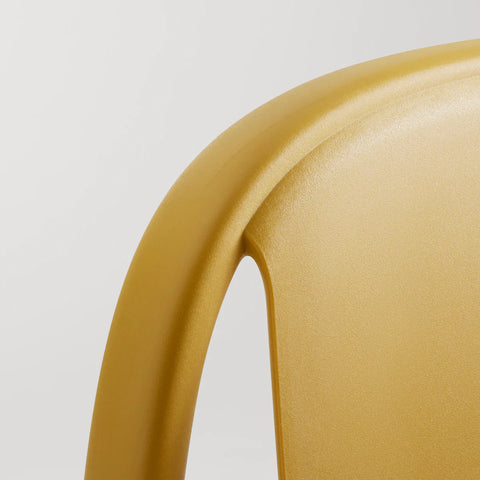 Blu Dot Decade Chair in mustard recycled plastic, close-up detail showing the textured surface of the seat back and curved frame