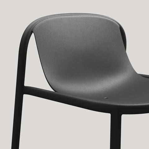 Blu Dot Decade Lounge Chair in black recycled plastic, close-up showing the seamless molded seat and back with integrated drainage hole