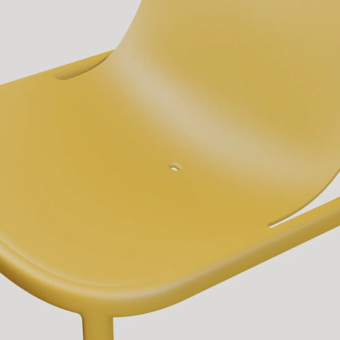 Blu Dot Decade Lounge Chair in mustard recycled plastic, close-up detail showing the integrated drainage hole in the seat for outdoor use
