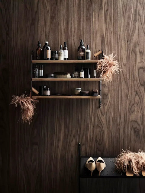 Walnut String® Pocket shelf styled with shoe care products and accessories on wood panel wall