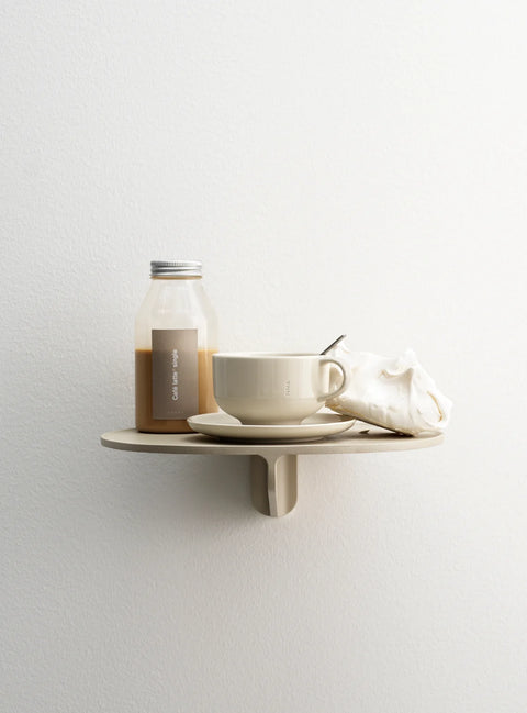 Museum NM&.045 shelf by String™ in beige styled with coffee cup, saucer, bottled drink, and seashell on white wall