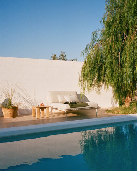 Muuto Settle Lounge Bed in laze grey by outdoor pool with Assemble Coffee Table in teak, modern Scandinavian patio setting