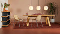 Two natural rattan Hint Chairs by Blu Dot at an oak dining table with pendant lights and a bookshelf