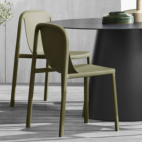 Blu Dot Decade Chairs in olive recycled plastic, styled around a black round dining table on a weathered wood patio