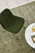 Top down lifestyle of Fredericia Eyes lounge chair in green next to a round marble coffee table on a sage rug
