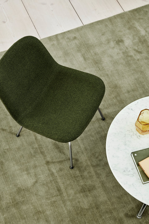 Top down lifestyle of Fredericia Eyes lounge chair in green next to a round marble coffee table on a sage rug