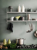 Galvanized String® System wall panels with shelves and hooks in a Scandinavian kitchen storage display