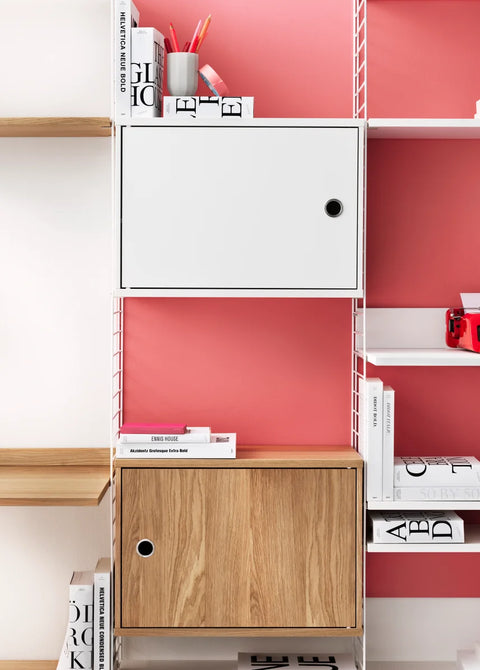 White and oak Cabinet with Swing Doors in String® System against pink wall