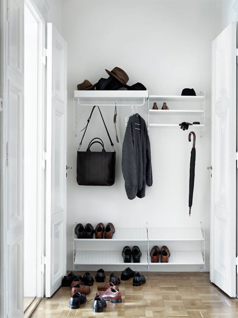 White String® System shoe shelves and wall storage in a Scandinavian entryway with coats, hats, and shoes