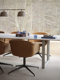 close up of cognac leather swivel dining chair with scandinavian lighting by muuto 