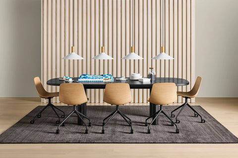 Blu Dot Good Times oval dining table in black oak styled with light wood swivel chairs and white pendant lights