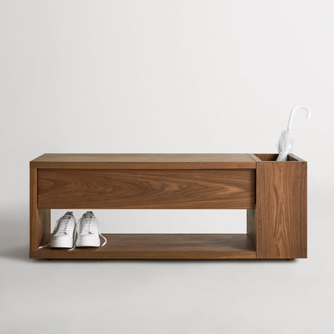 Blu Dot Go Forth Bench in walnut with shoes on bottom shelf and umbrella in side storage compartment.