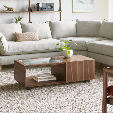 Gus* Modern Conway Coffee Table, walnut coffee table with books in the open cubby, in front of a sectional sofa