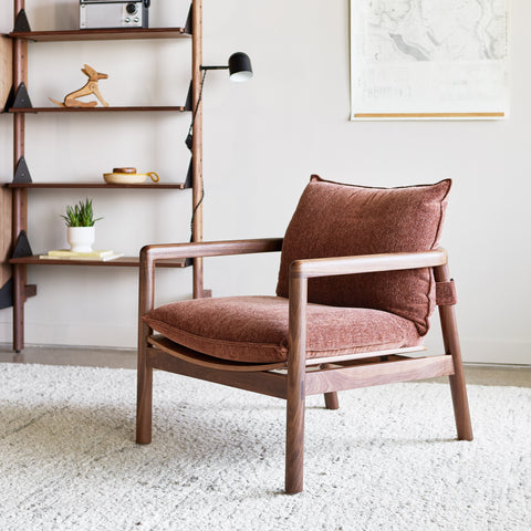 Gus* Modern Humber Lounge Chair, walnut lounge chair, Regency Beet cushions in a room with walnut wall shelving