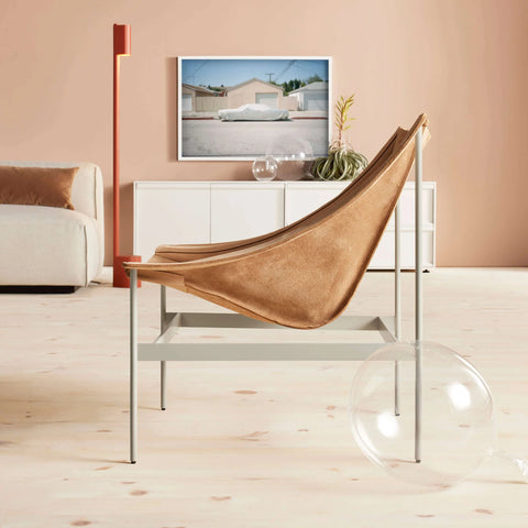 Blu Dot Heyday Lounge Chair in sand leather with a white steel frame in a modern living room with a peach accent wall