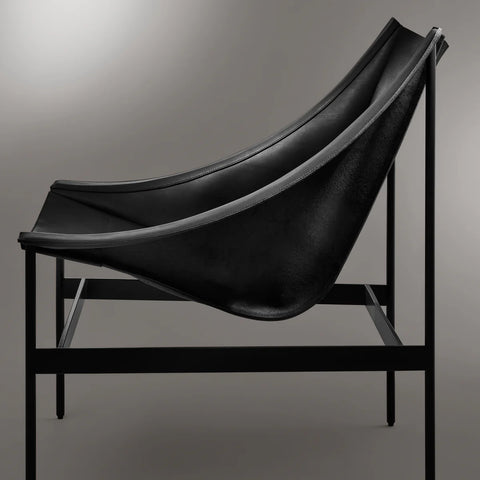 Side view of the Blu Dot Heyday Lounge Chair in black leather showing the suspended sling seat and black steel frame