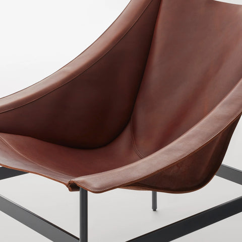 Close-up detail of the Blu Dot Heyday Lounge Chair showing the chestnut full-grain leather sling seat and black steel frame