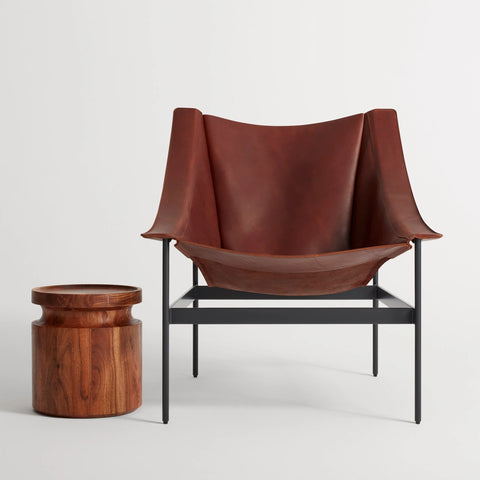 Blu Dot Heyday Lounge Chair in chestnut leather with a black powder-coated steel frame styled next to a round wood side table