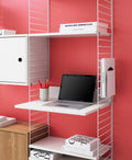 String System shelving with white media shelf styled as a compact home office desk with laptop and books