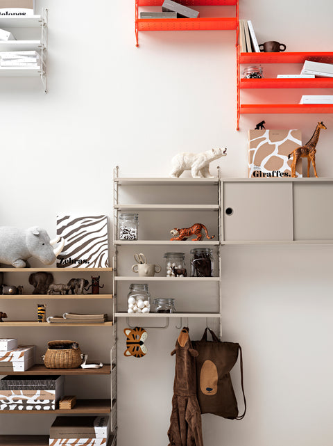 Children’s room with String® System shelving in beige and neon accents, featuring low metal shelves styled with toys, books, and storage jars