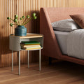 Putty Li'l Something Side Table by Blu Dot with a white oak top used as a nightstand, holding books and a vase
