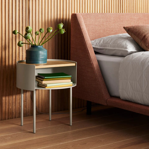 Putty Li'l Something Side Table by Blu Dot with a white oak top used as a nightstand, holding books and a vase