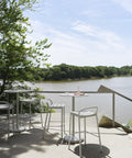 muuto steel linear bar stool in white on a patio overlooking a lake